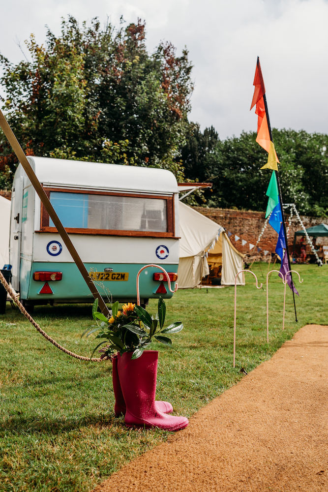 shot of a honeymoon bell tent and caravan set next to a marquee entrance as part of a festival wedding