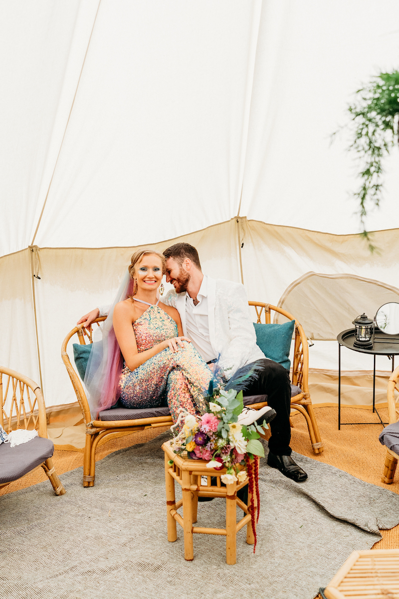 bride and groom sat together inside their honeymoon bell tent