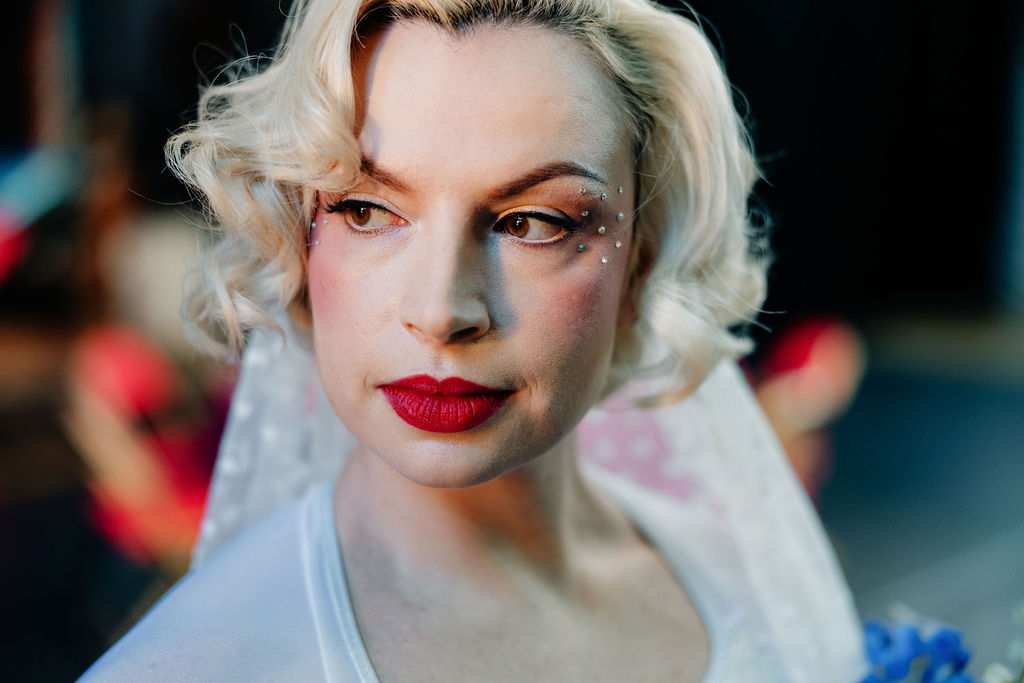 detail shot of brides bold red lipstick and face gems
