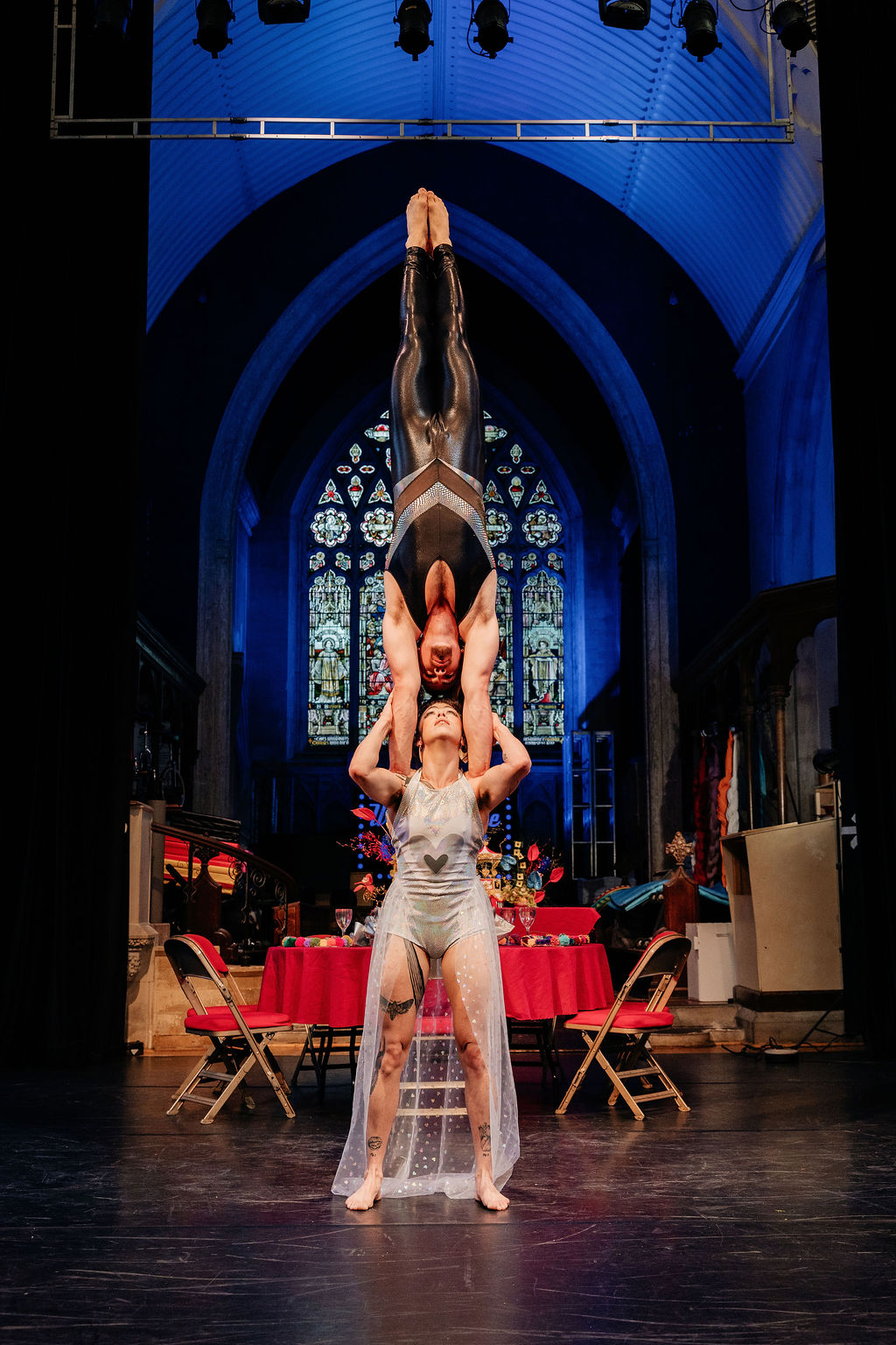 alternative couple portrait - bride holding groom above her head as part of a circus performance