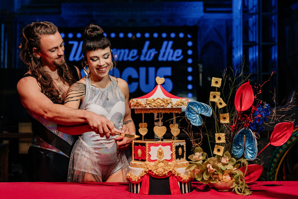 bride and groom cut a fairground carousel inspired wedding cake