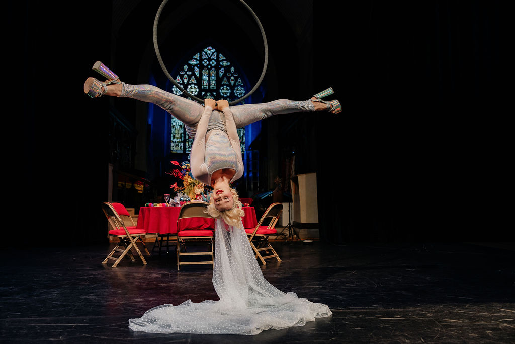 bride hanging upside down from an areal hoop at circus school wedding
