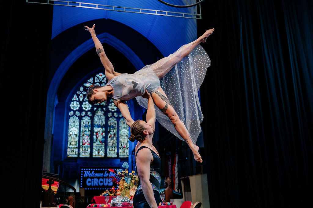 bride wearing alternative wedding wear held in the air for circus performance