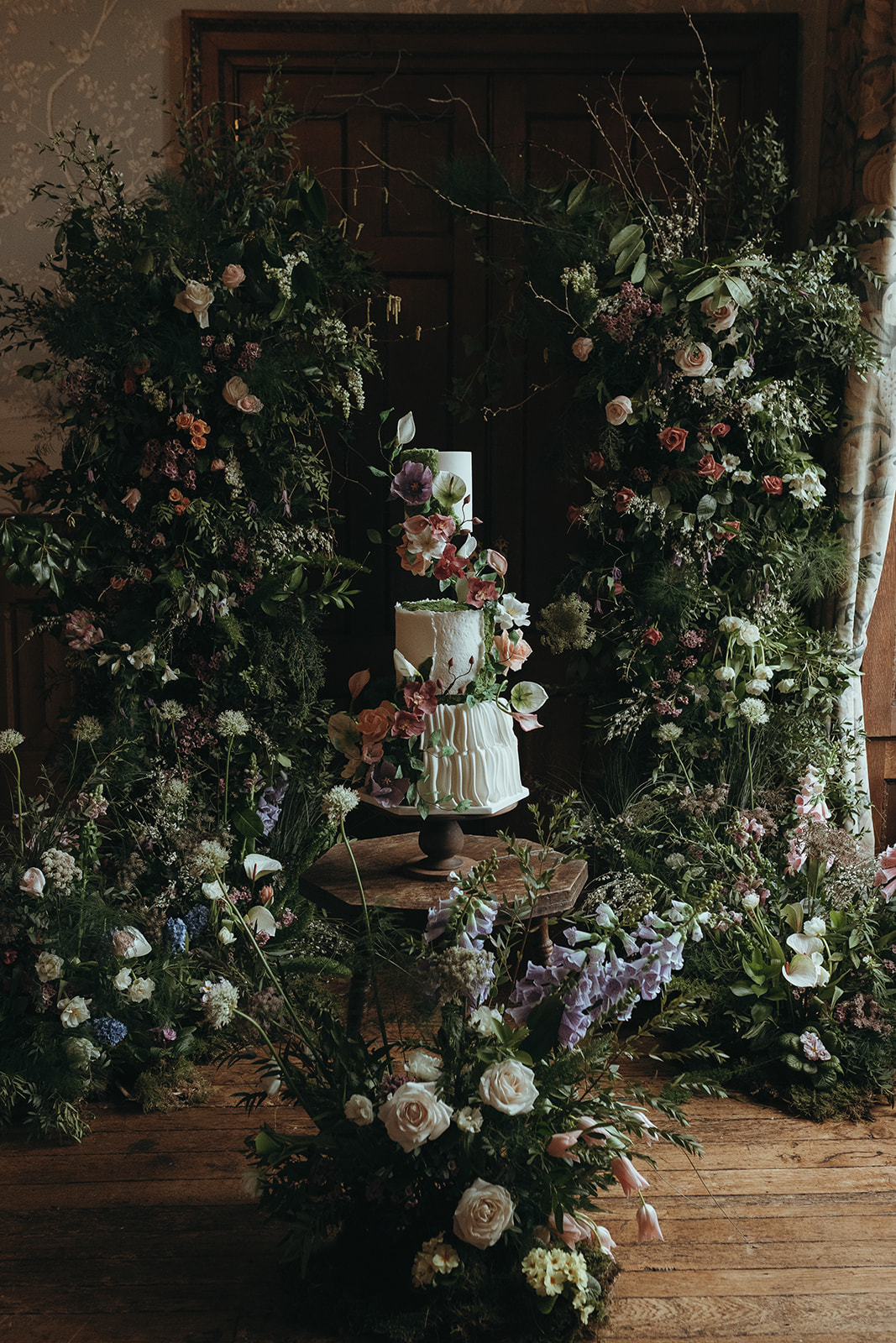 detail shot of a statement flower installation and floral wedding cake for enchanted woodland wedding