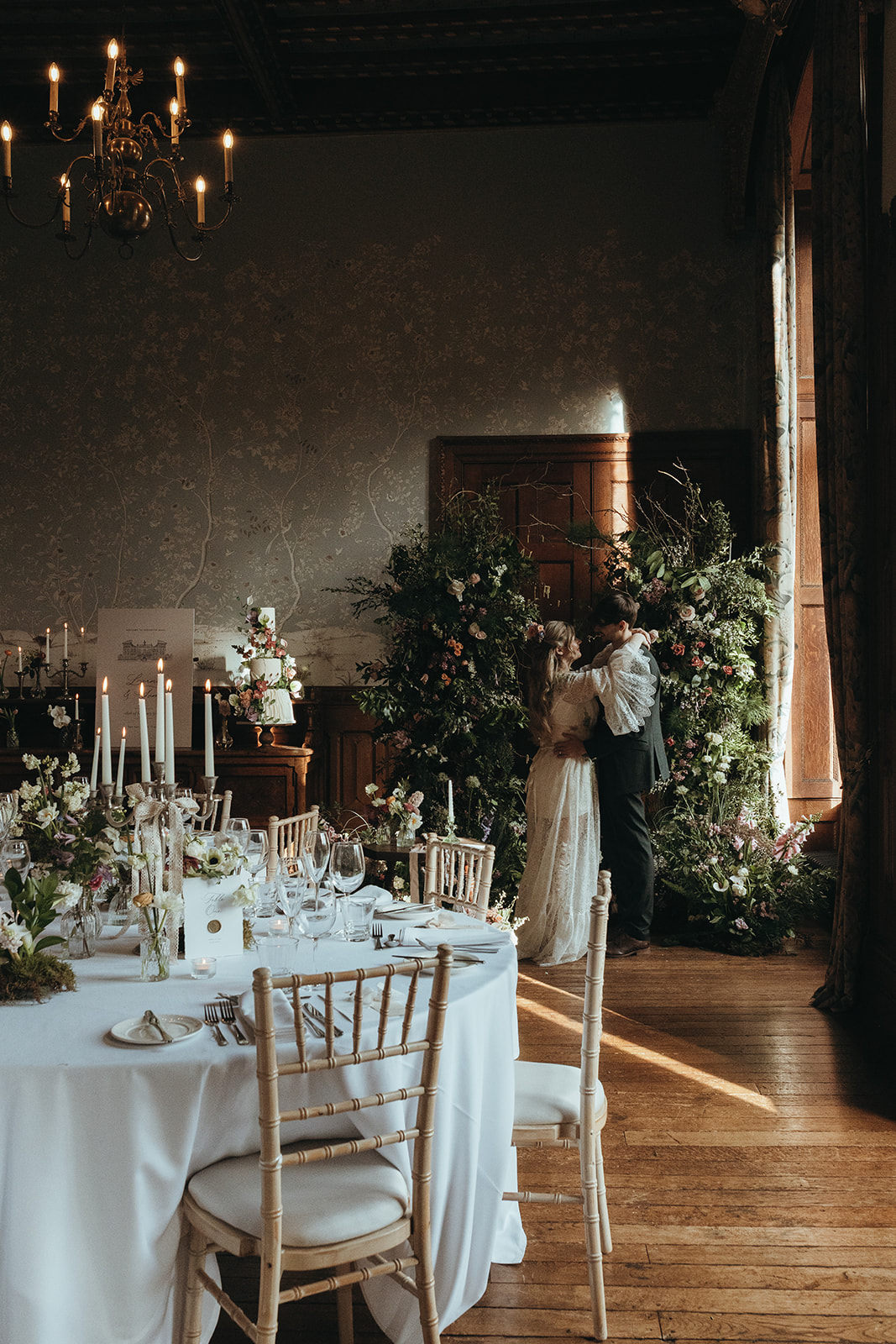 bride and groom within their wedding venue with floral ceremony space and candle lit wedding breakfast tables
