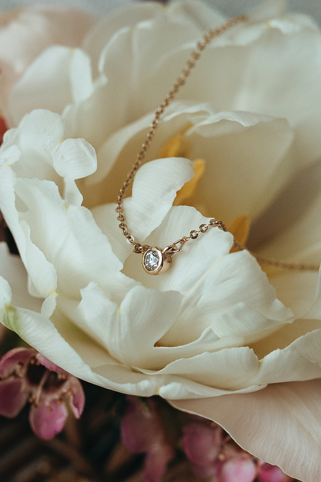 detail shot of a gold and diamond necklace sat on wedding flowers