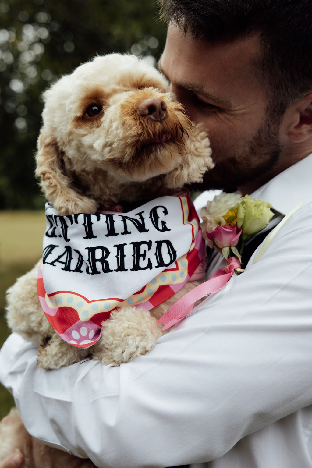 groom holding dog wearing my humans are getting married bandana