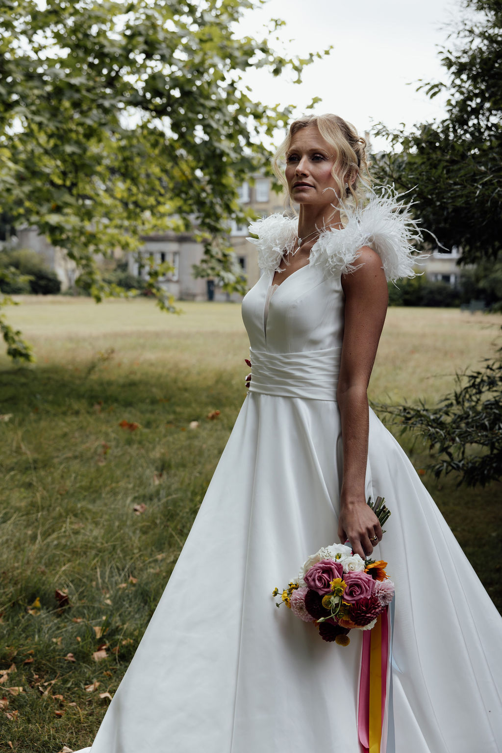 bride wearing feather shouldered wedding dress stood in her parkland wedding venue