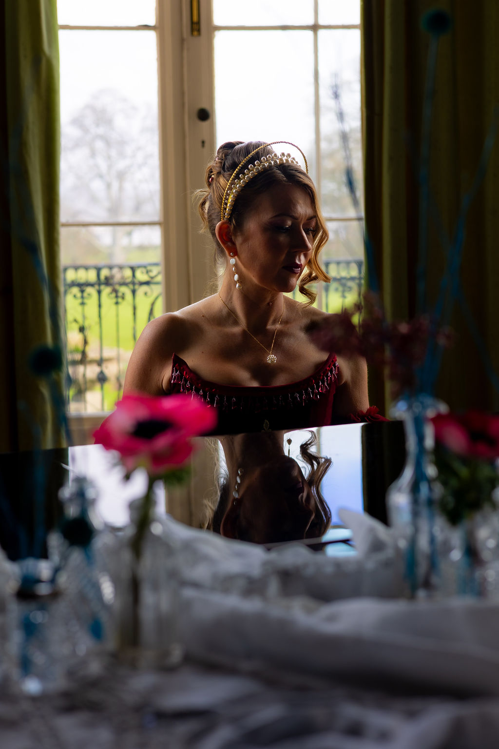 atmospheric shot of a bride sat at a piano. her silhouette is reflected on the piano