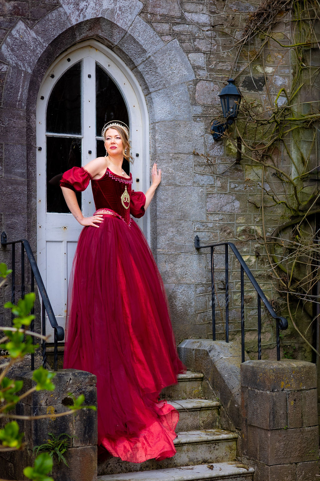 bride wearing red wedding dress stood in a doorway outside Powderham Castle