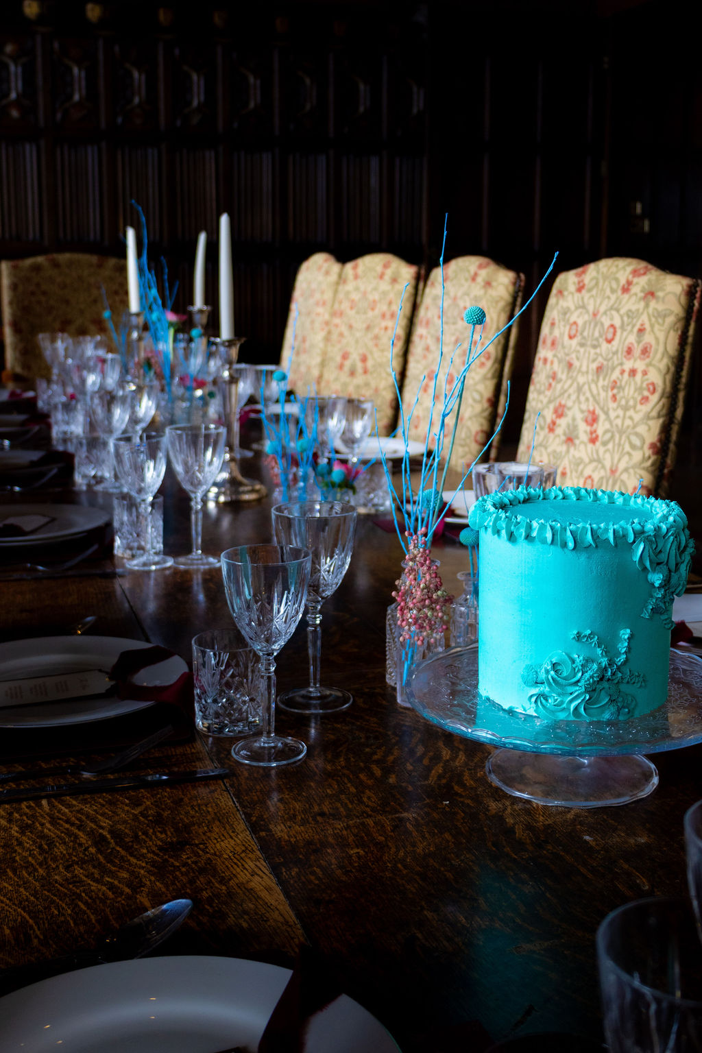 turquoise wedding cake stood on a banquet table with architectural flowers