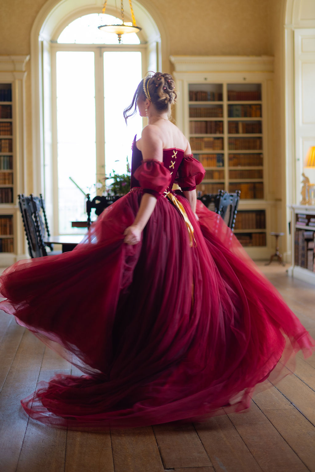 bride twirling in her red wedding dress in the library of a castle wedding venue