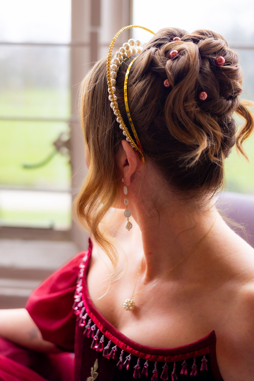 detail shot of bridal updo finished with red pearl hair pins