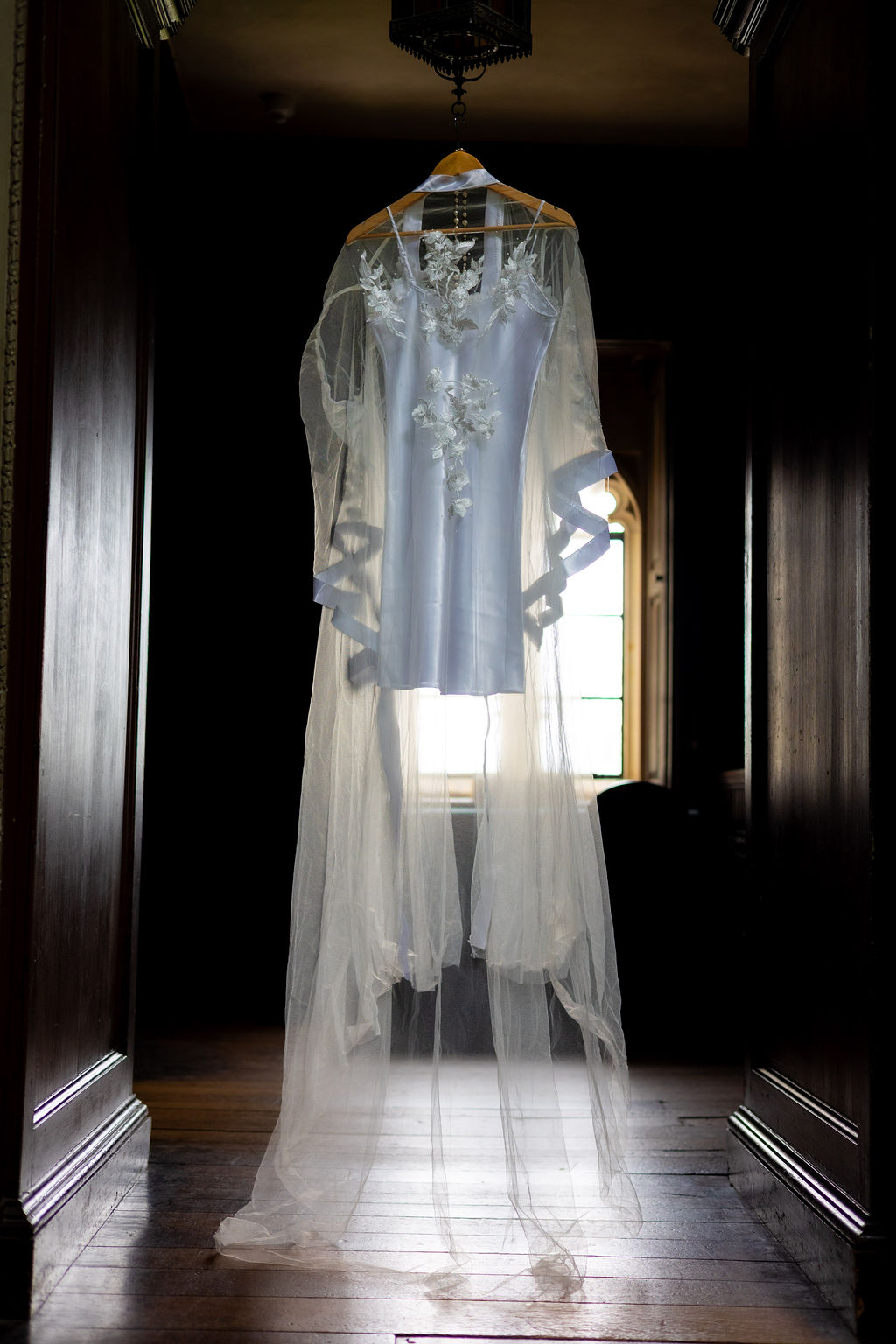 tule bridal robe with floral embroidery back lit by castle window.