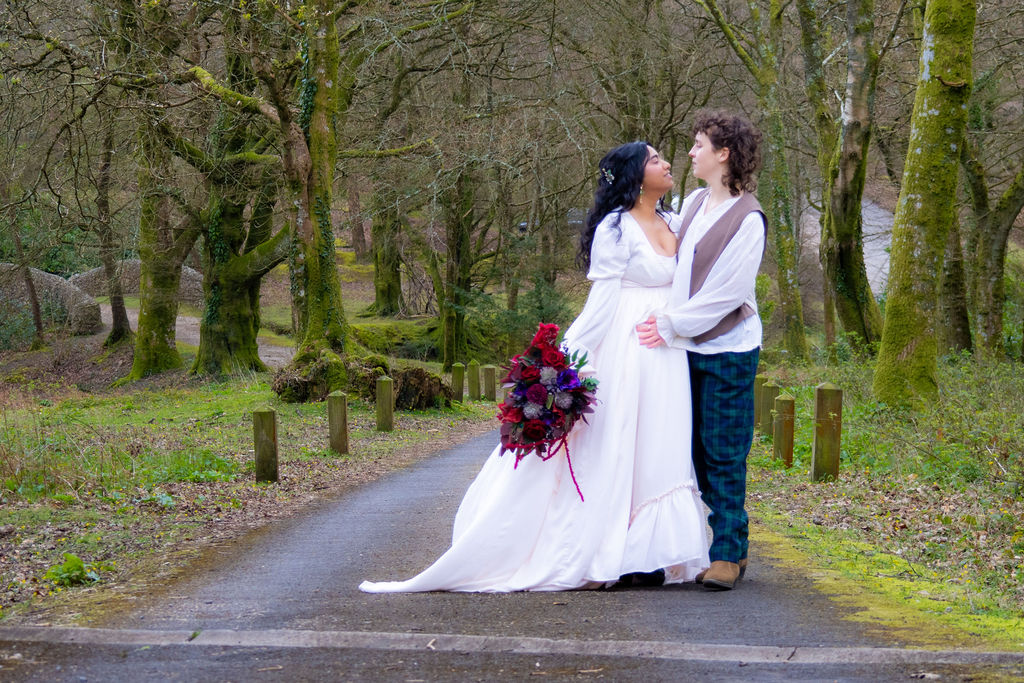 couple portrait on the driveway of historical wedding venue with ancient woodland around them