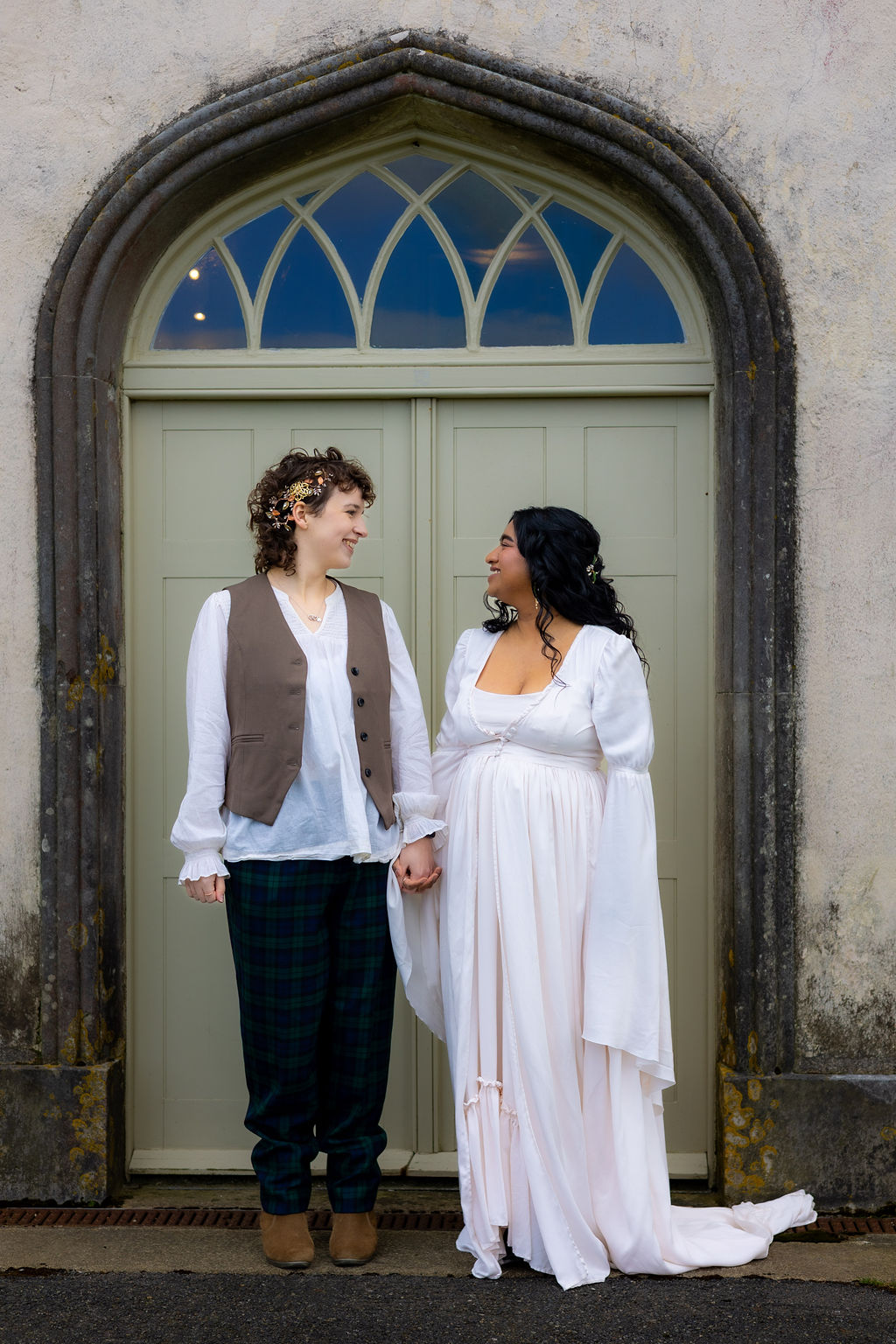 LGBTQ couple holding hands in the door way of their historical Devon wedding venue