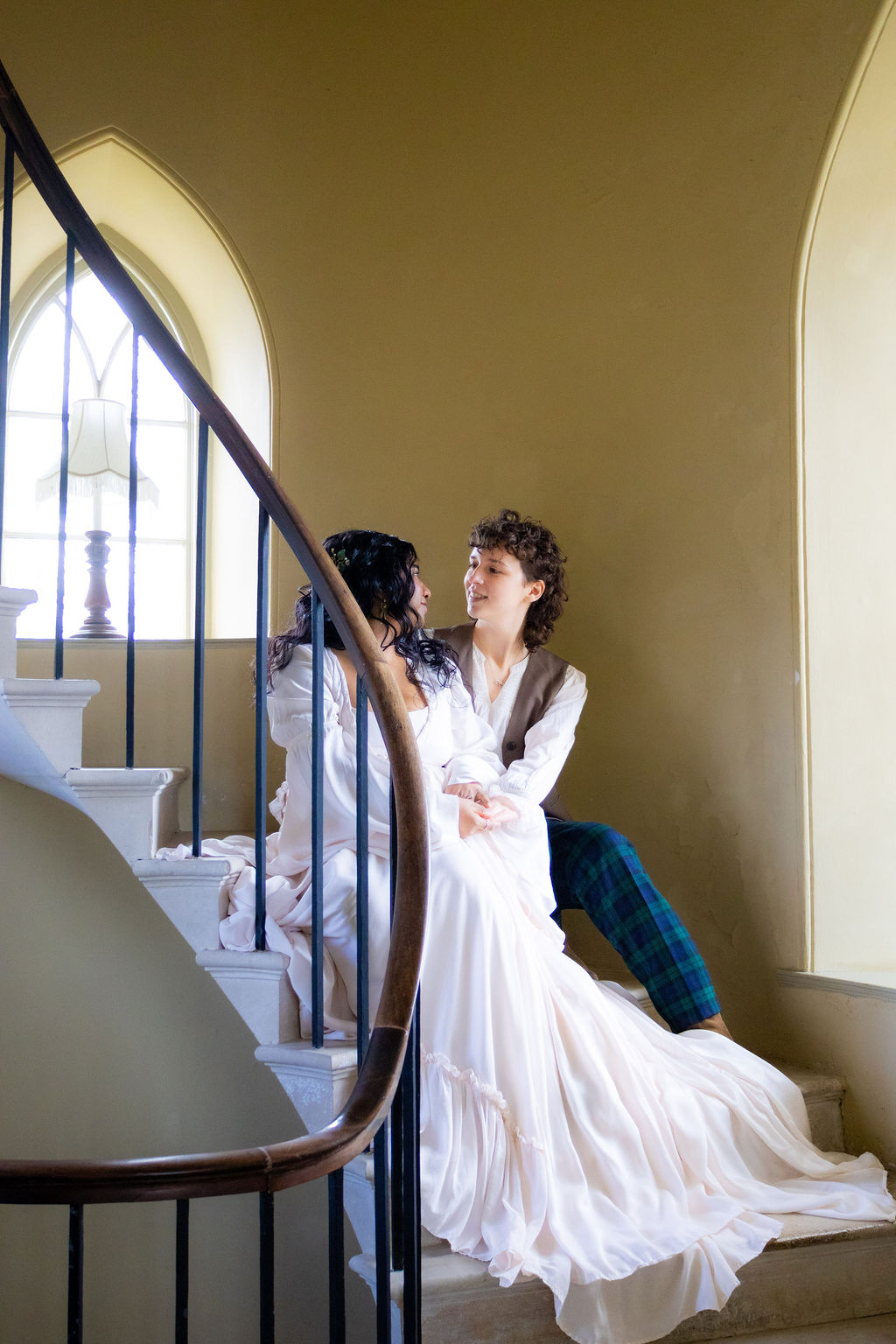 couple sitting on the circular staircase of their historic wedding venue