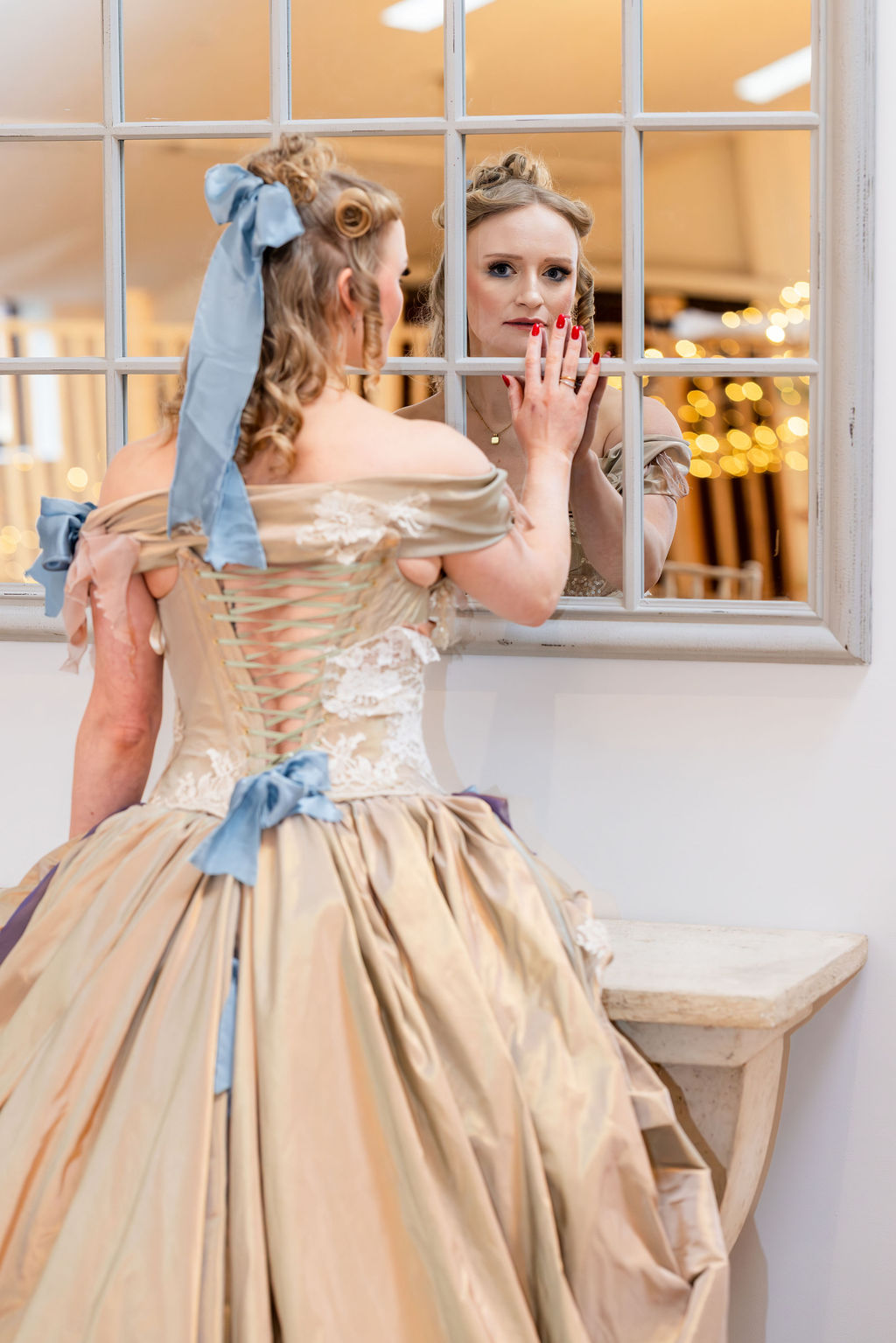 bride model looking in the mirror wearing corseted gold and blue dress