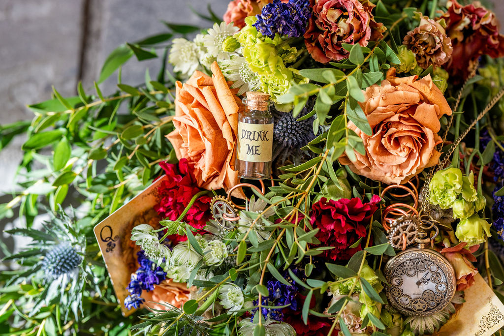 Alice in wonderland inspired wedding flowers with drink me bottle and pocket watch