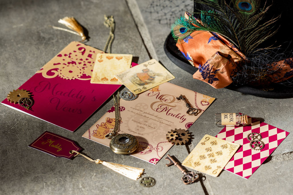 flat lay of wedding stationery inspired by Alice in Wonderland with a steampunk twist