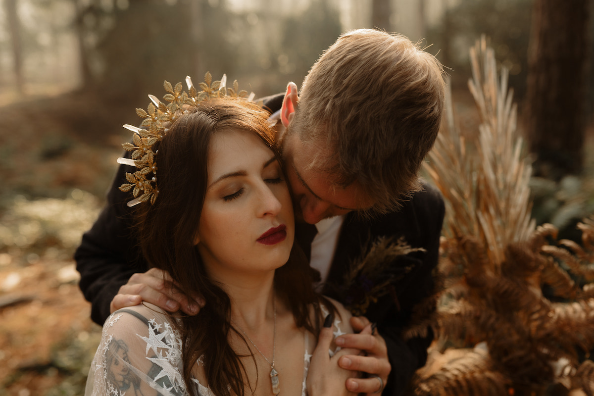 bride wearing gold leaf crown with quartz being embraced from behind by her husband
