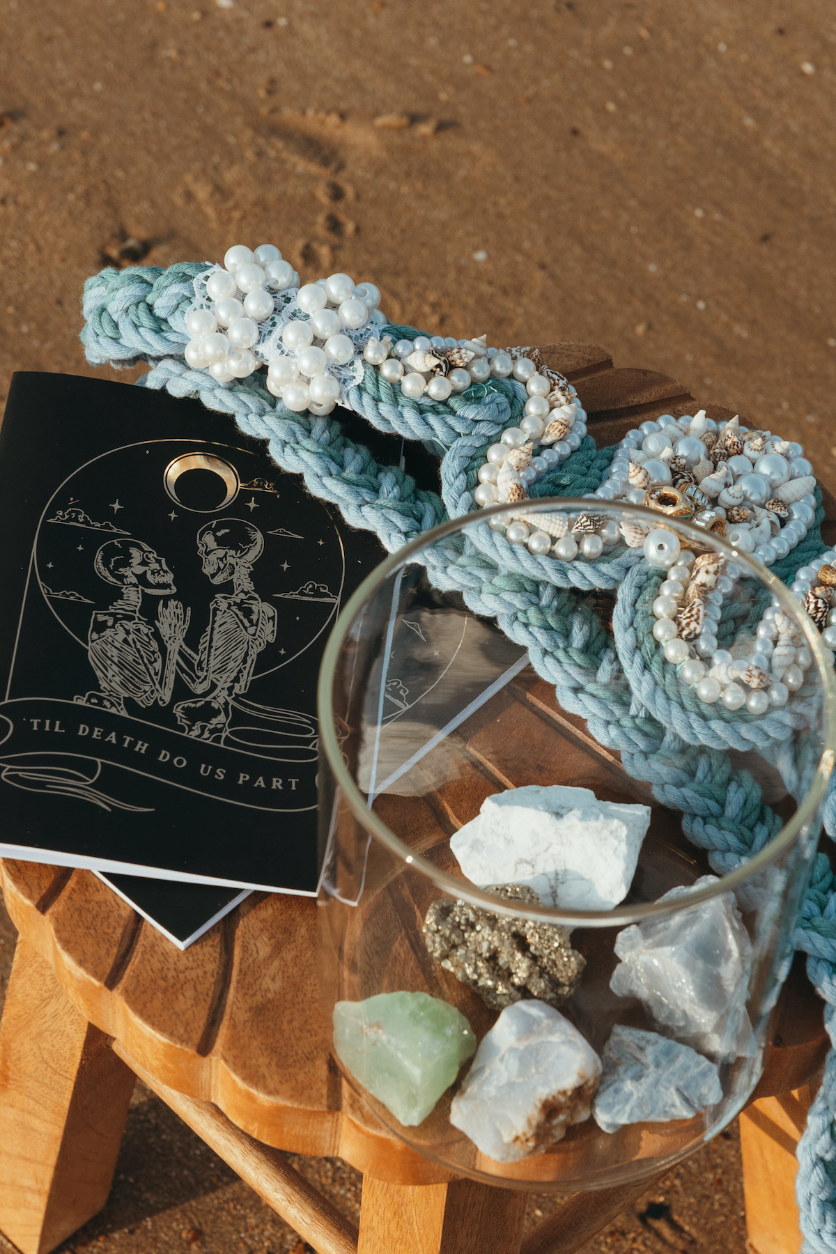 flat lay shot of crystals in a jar, vow book and ocean inspired hand fasting cord