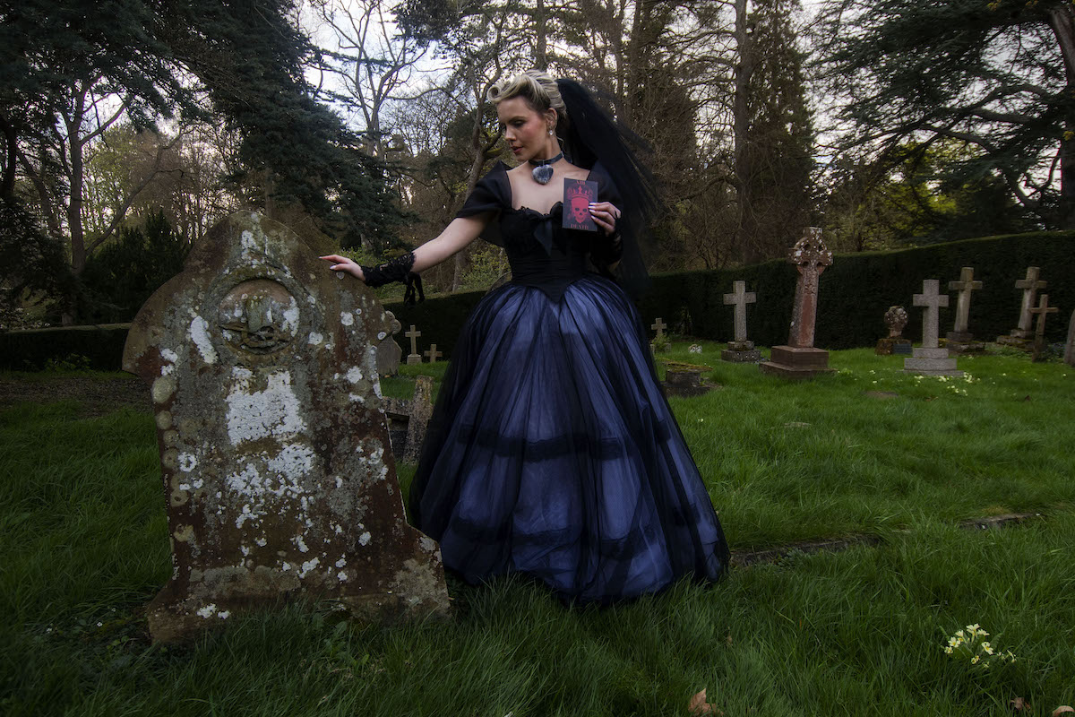 bride wearing black wedding dress stood in a grave yard for Wuthering Heights inspired wedding