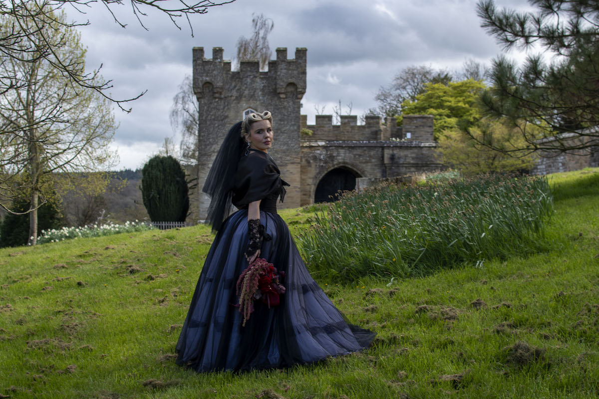 bride wearing black stood in front of a tower for Wuthering Heights inspired wedding