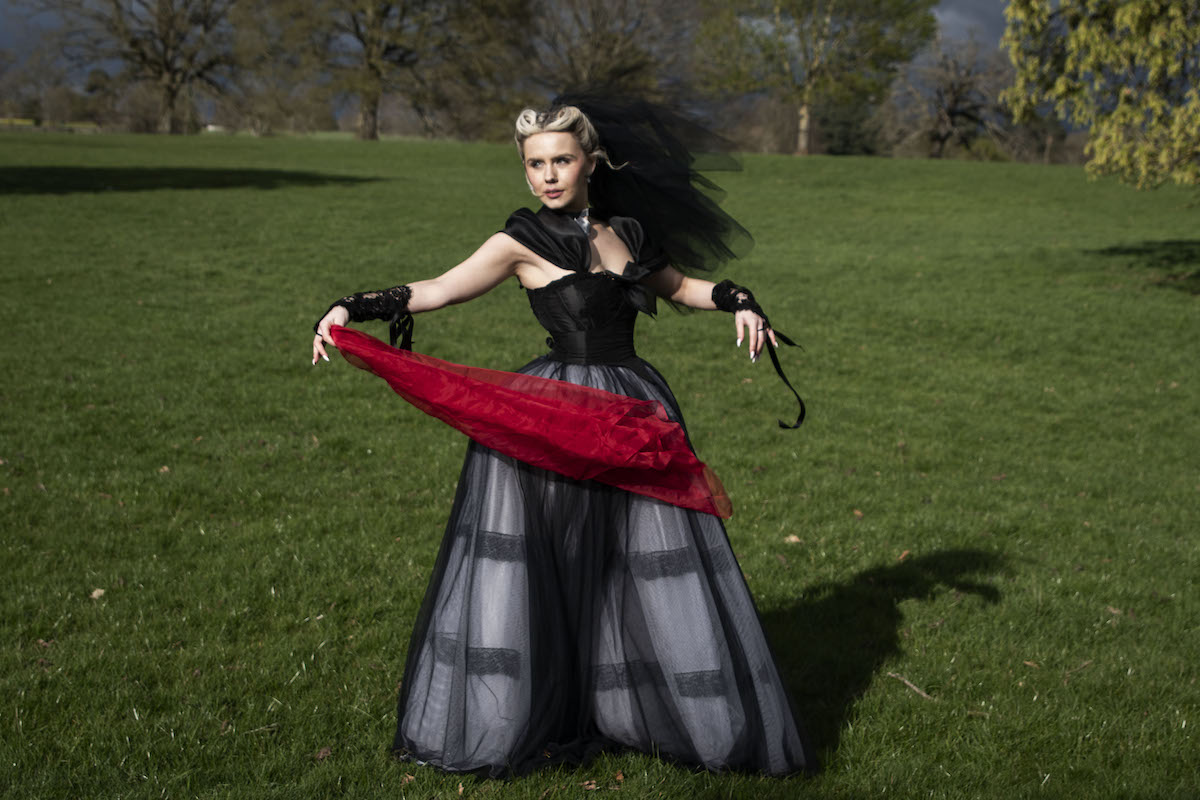 bride in black wedding dress and veil holding a red scarf to depict the finale of Wuthering Heights