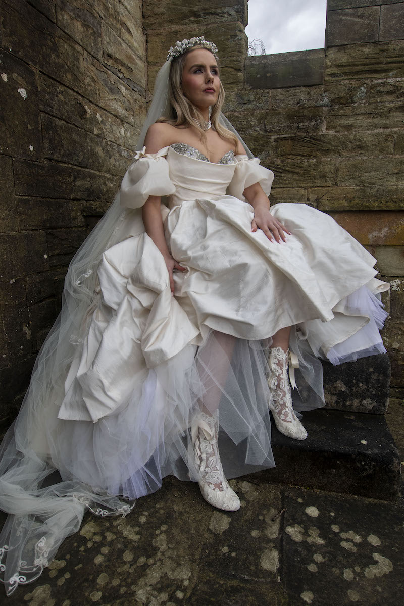 bride holding up ballgown dress to show lace wedding boots