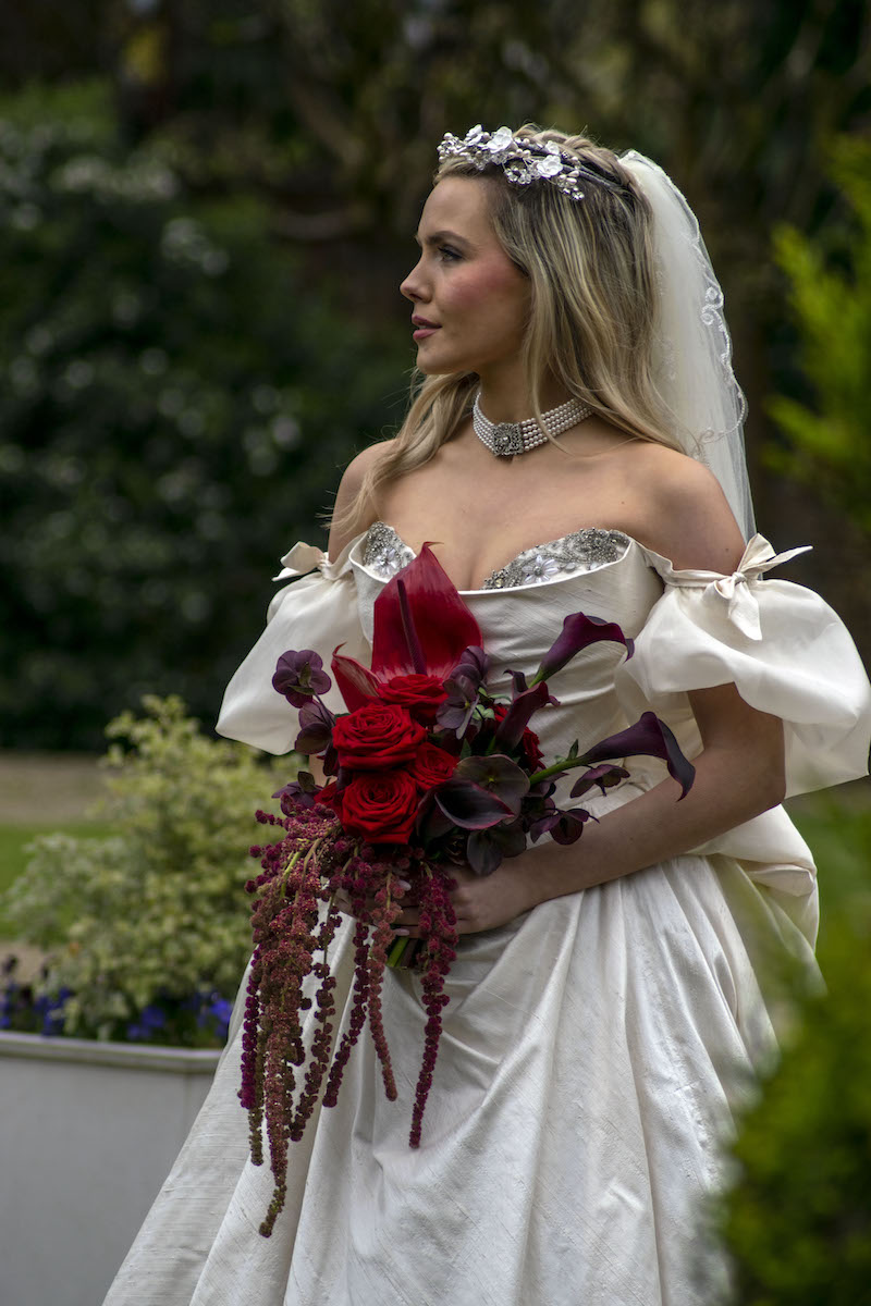 bride wearing large ballgown style dress holding a statement deep red wedding bouquet