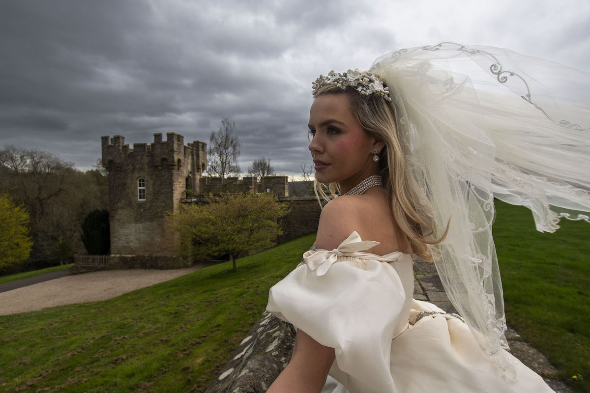 bride leaning on the wall with the wind blowing her veil for a Wuthering Heights inspired portrait