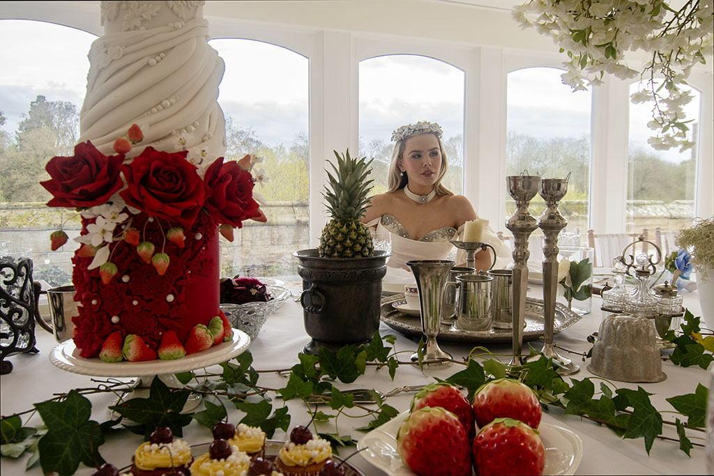 bride sat at wedding breakfast table surrounded by pewter candle sticks, ivy and deserts