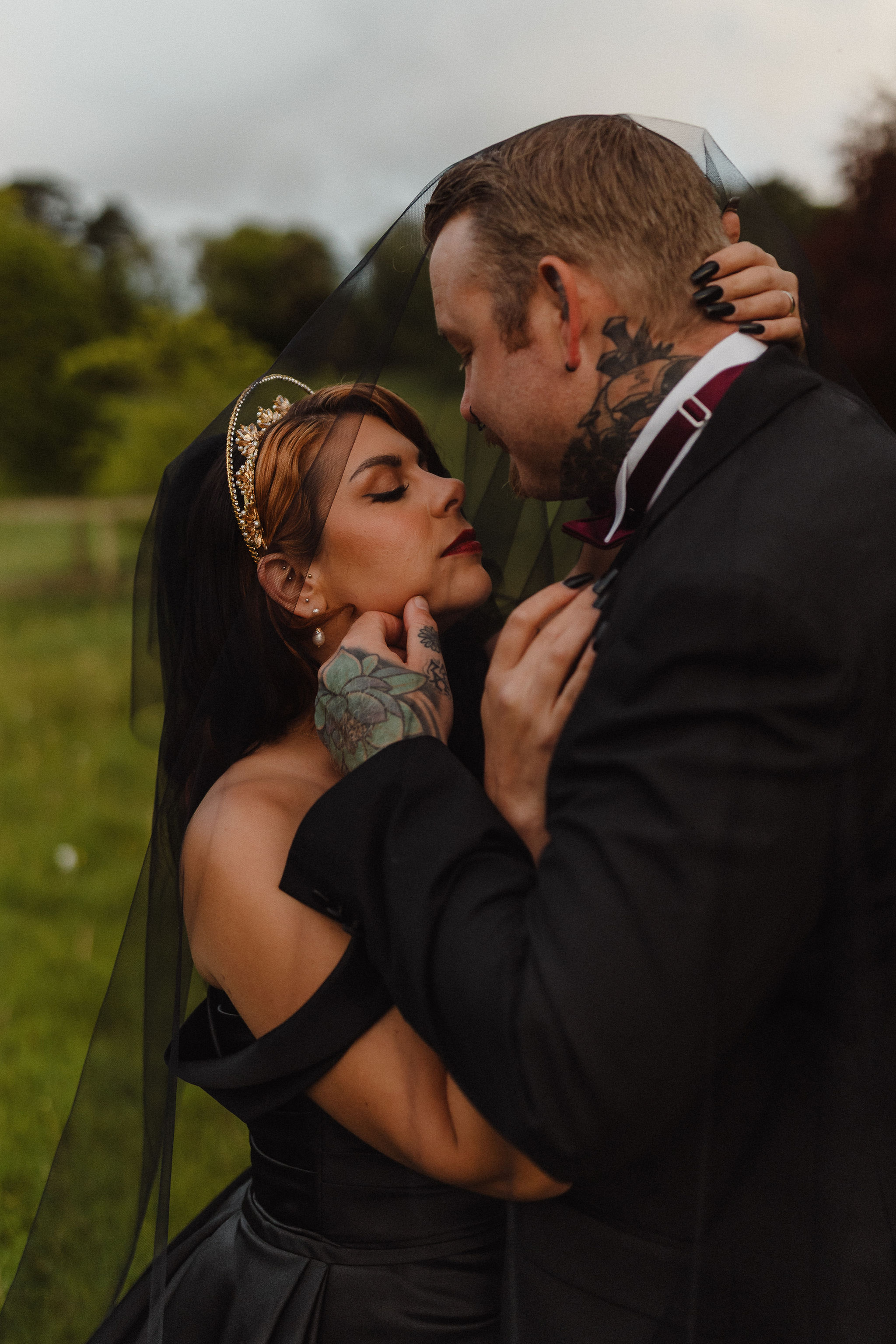 bride and groom under the black veil about to kiss