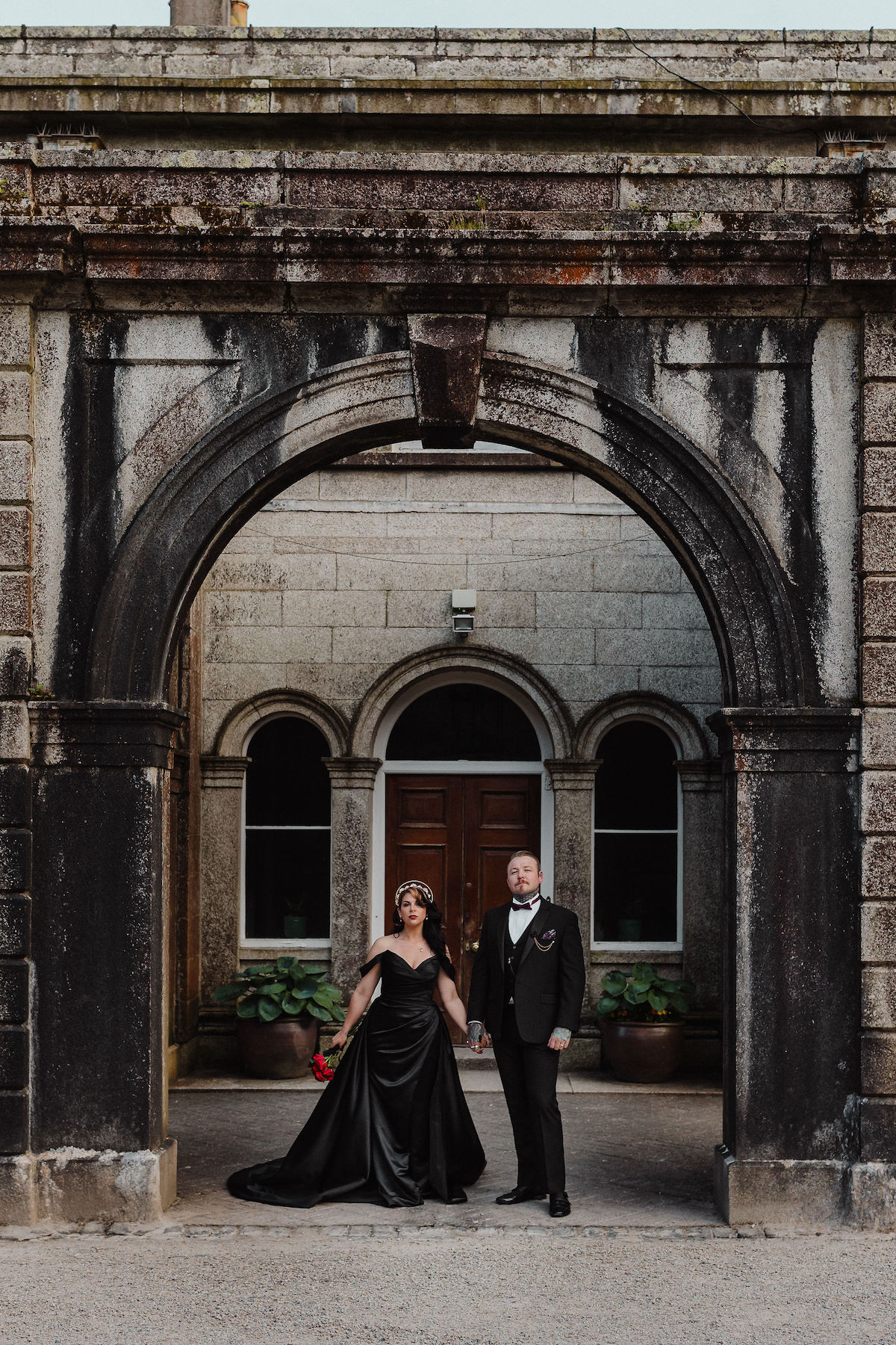 bride wearing black wedding dress stood with her groom outside of their Cornwall wedding venue