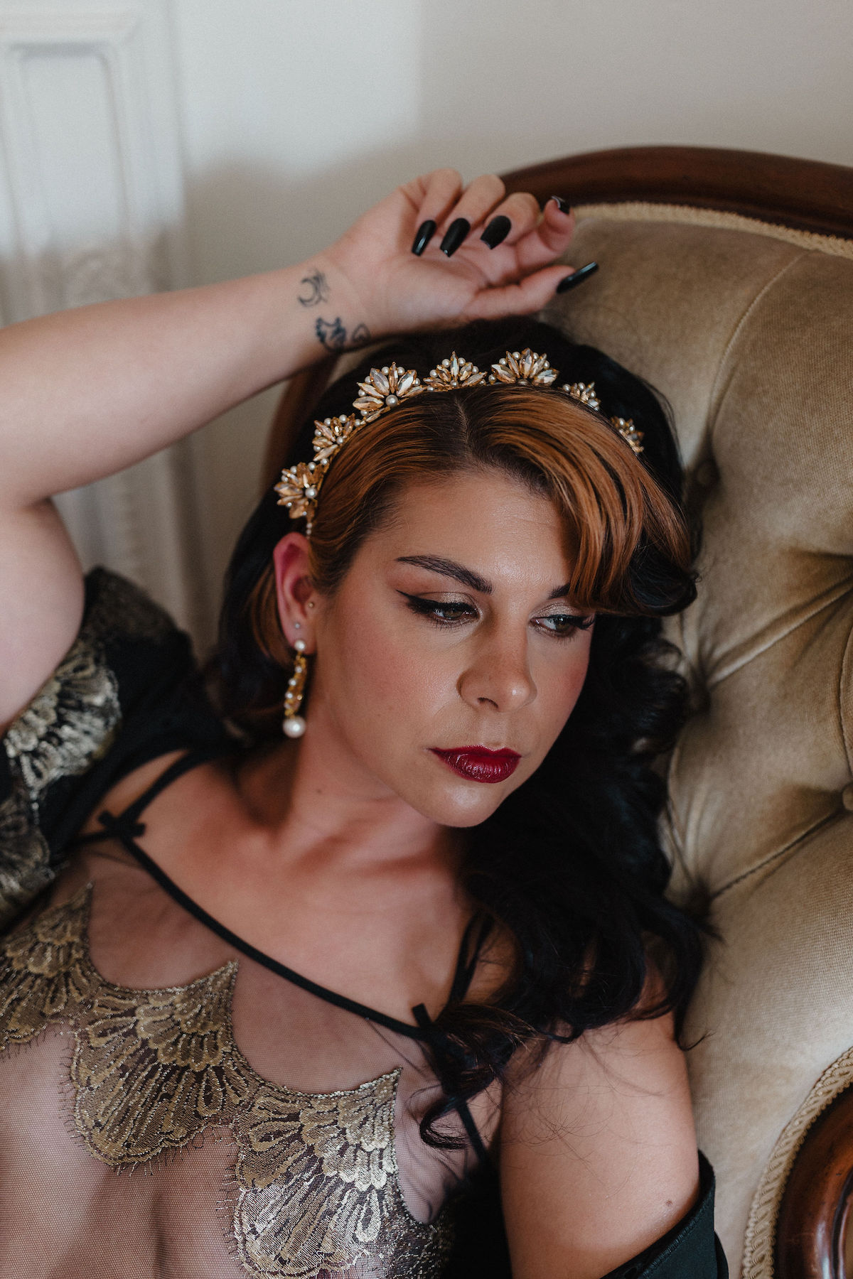 boudoir photo of bride wearing black and gold deco lingerie and deco style crown and earrings