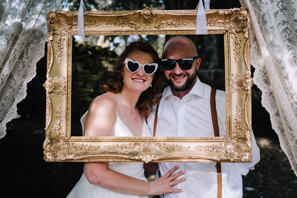 bride and groom pose in vintage frame thrifted from a charity shop