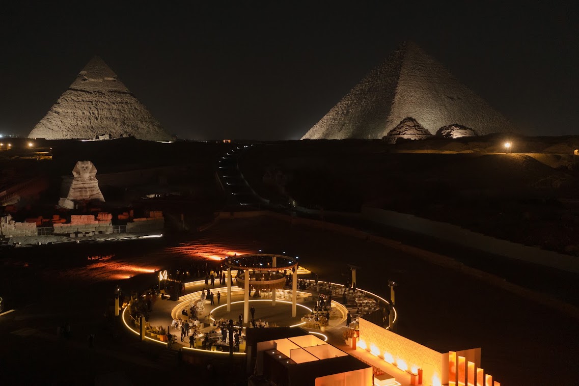 nighttime overview photo of wedding reception space set up in front of a Sphinx and pyramids