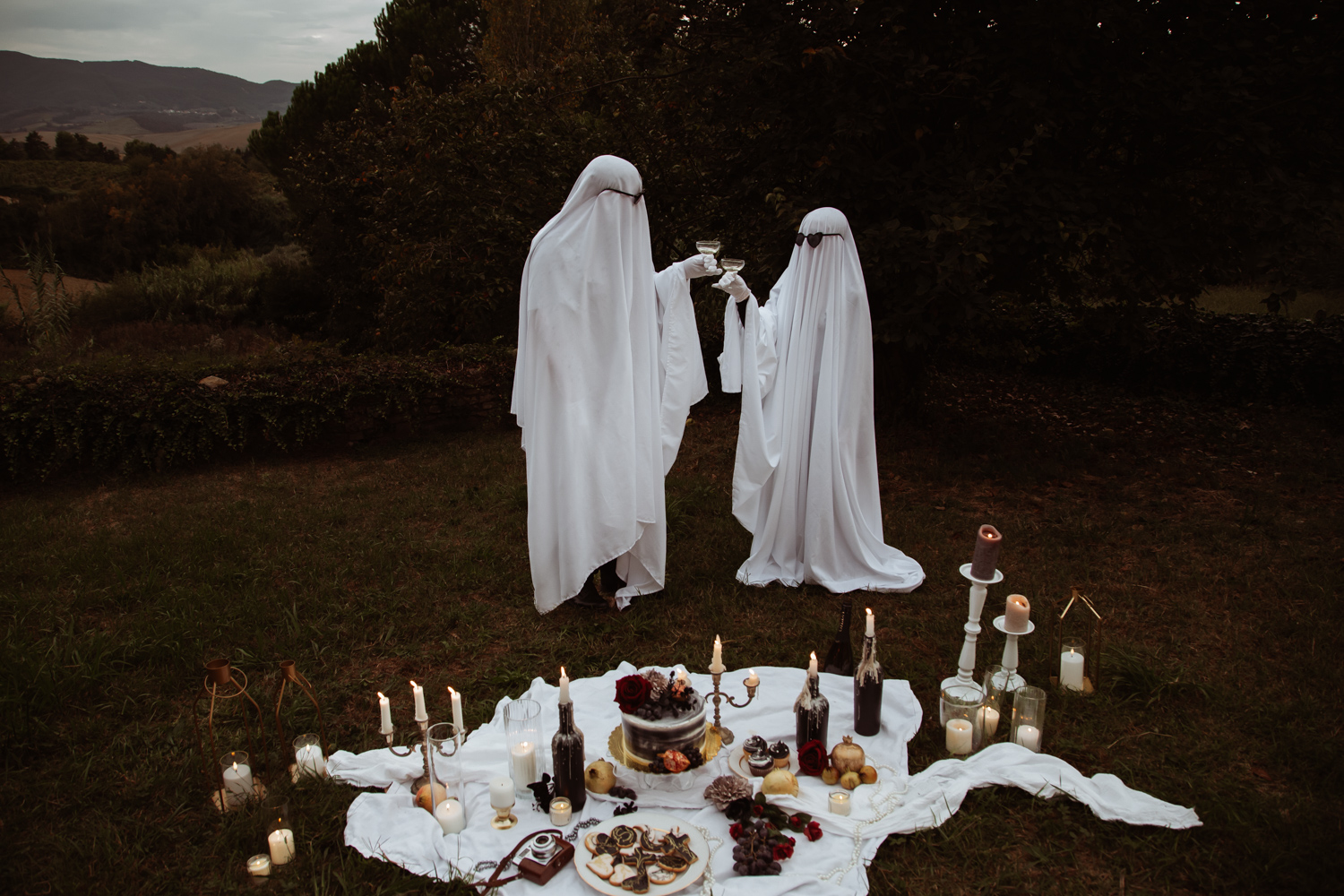 couple dressed as ghosts wearing sunglasses toast with champagne for alternative halloween wedding portrait