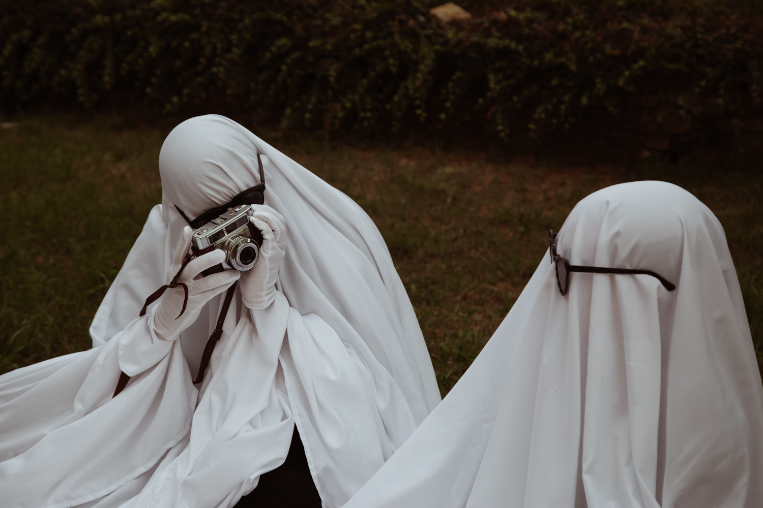 playful Halloween wedding couple portrait where groom dressed as a ghost photographs his ghost bride
