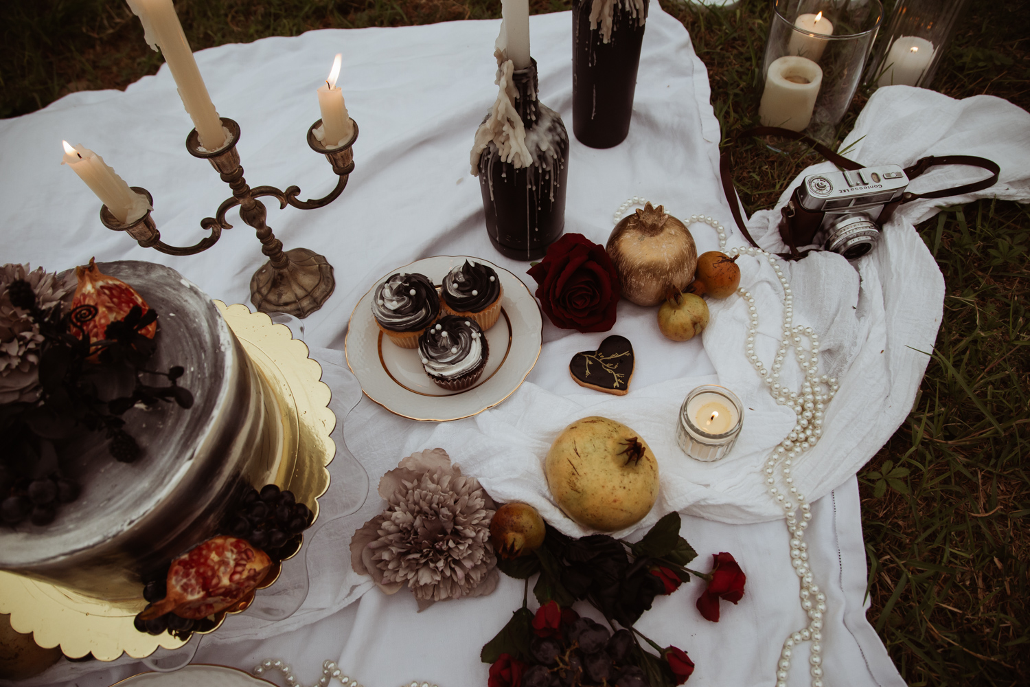 wedding breakfast picnic details with gold pomegranates, candles, strings of pearls and sweet treats