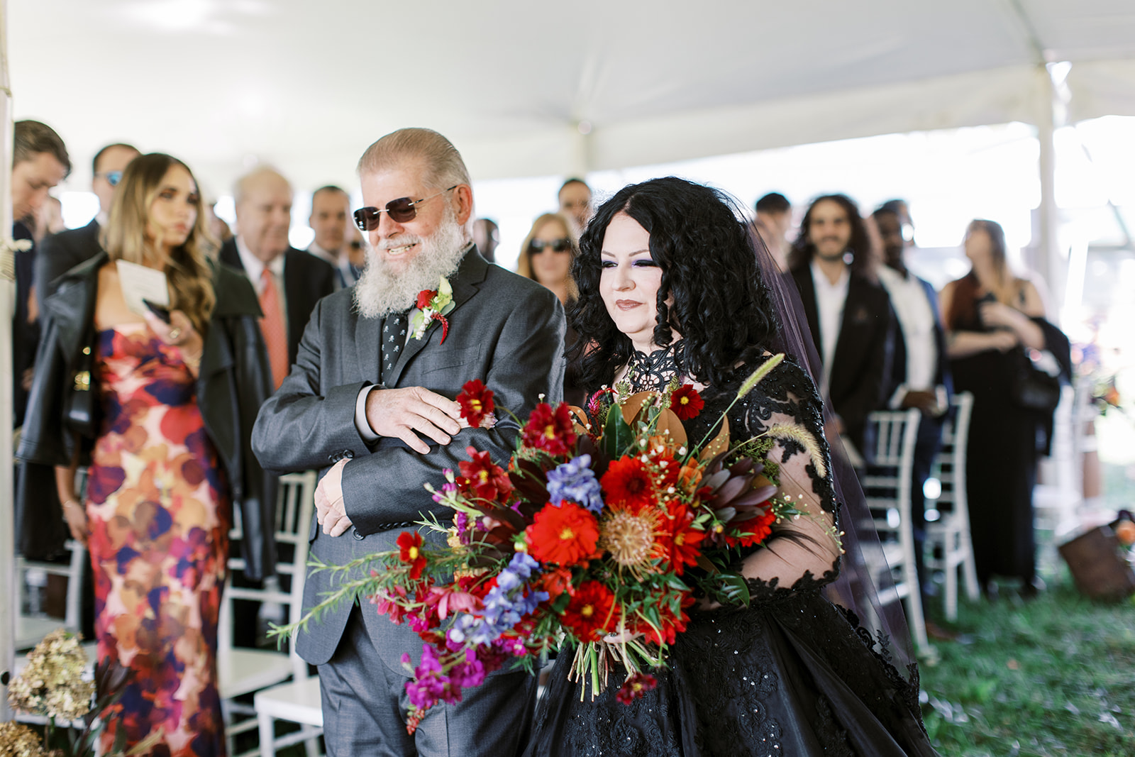 bride in black walking down the aisle with her proud father