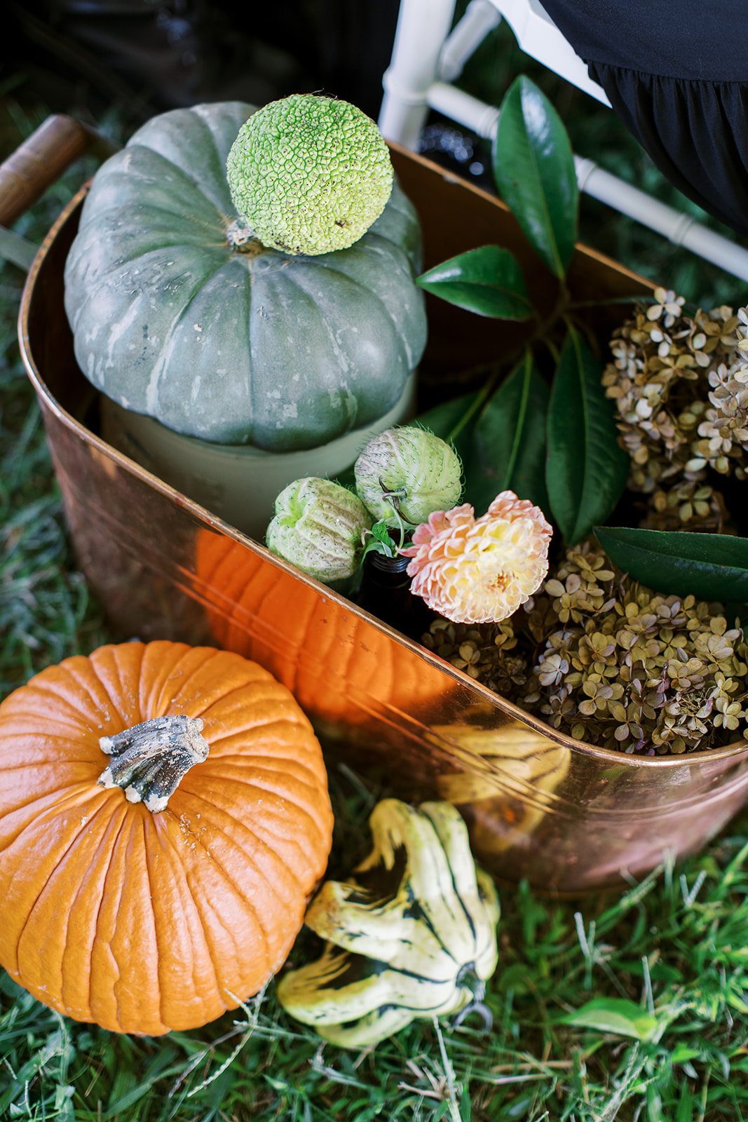 copper trough containing flowers and pumpkins for halloween wedding aisle
