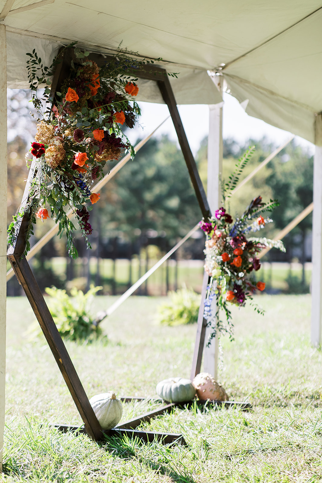 orange flowers on a hexagonal ceremony arch with pumpkins for halloween wedding