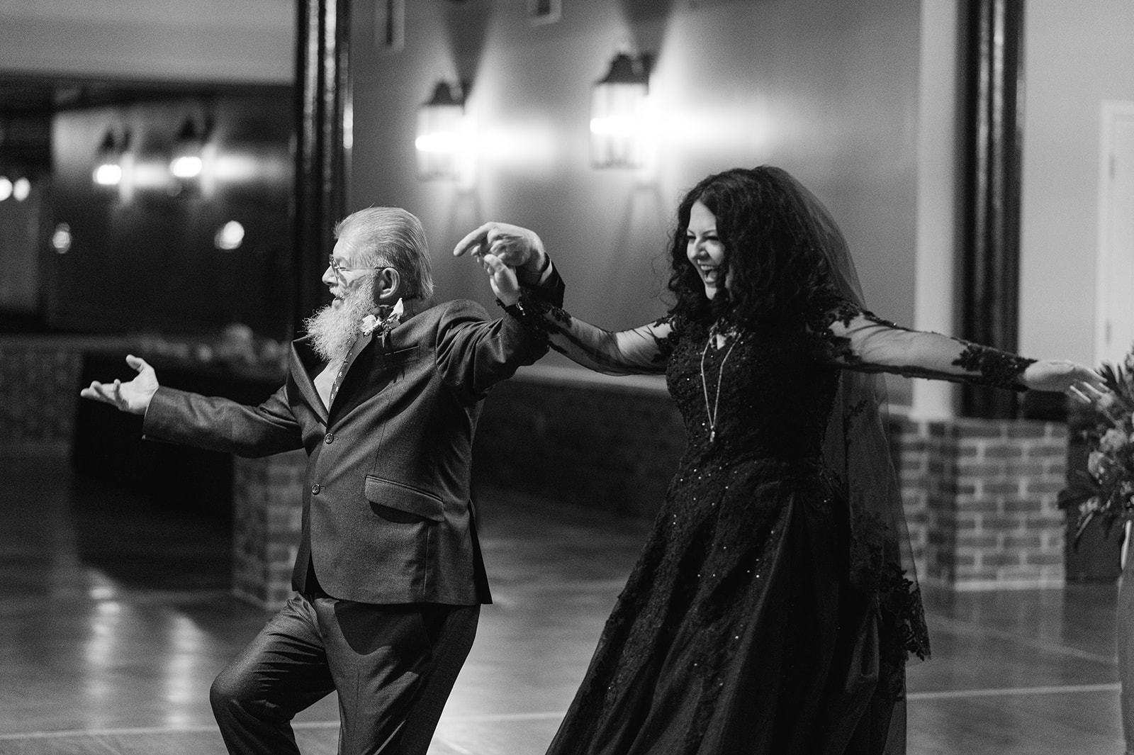 Bride in black dancing looking overjoyed dancing with her father