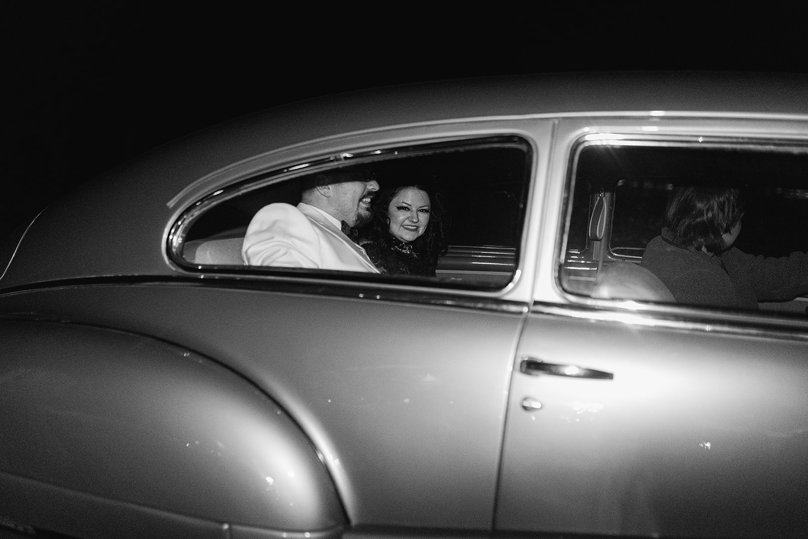 Newly weds in an old American wedding car leaving their Halloween wedding reception