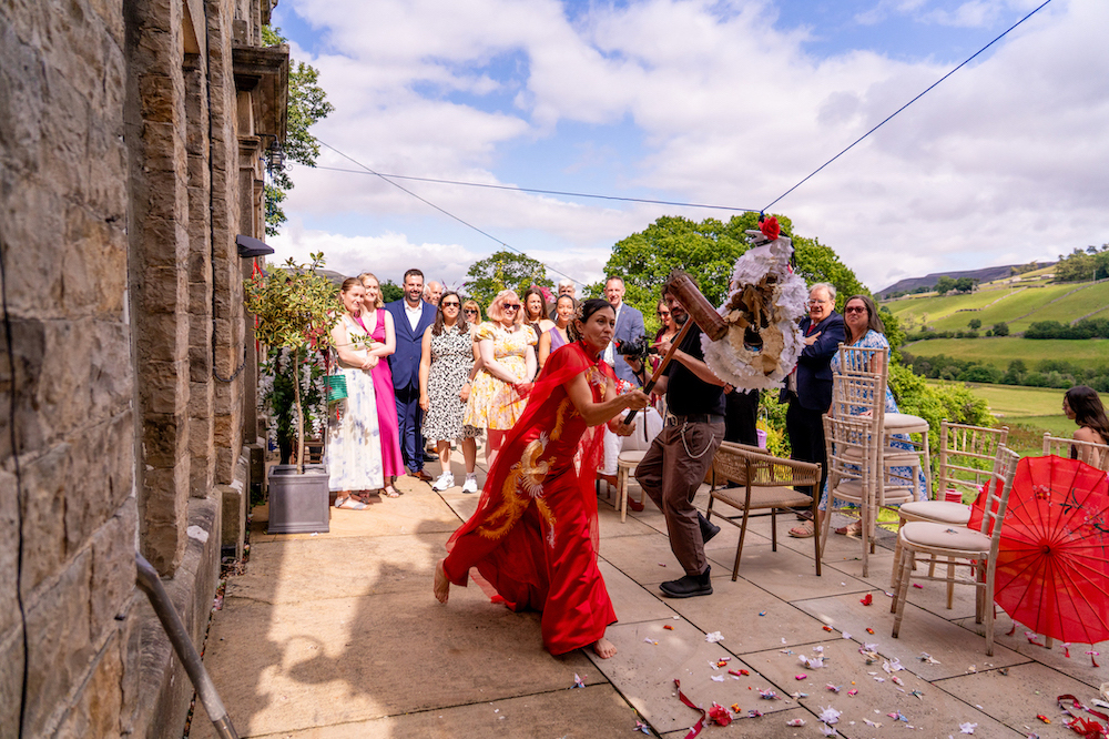 bride hitting a homemade piñata with a croquet mallet at fusion wedding in Yorkshire