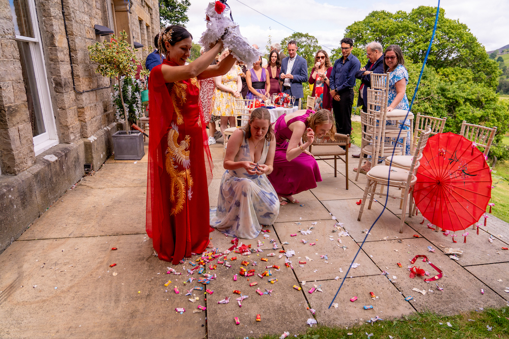 bride in red emptying handmade wedding piñata