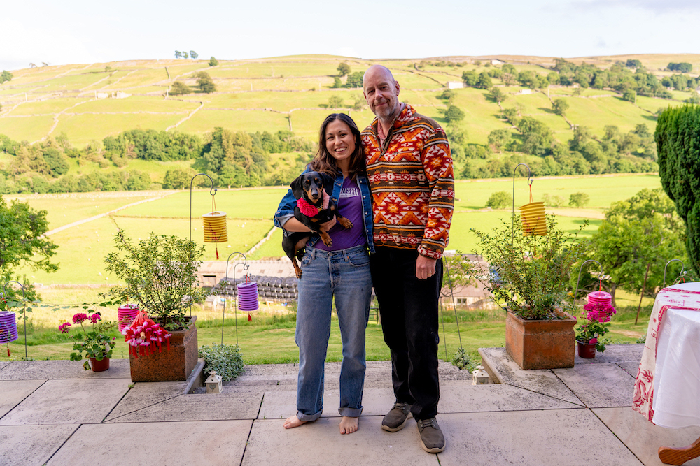bride and groom wearing casual clothes posing with their pet dog at Yorkshire fusion wedding