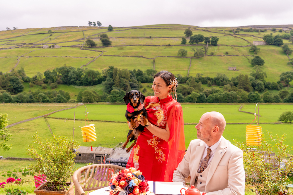 bride holds their sausage dog during signing of the register